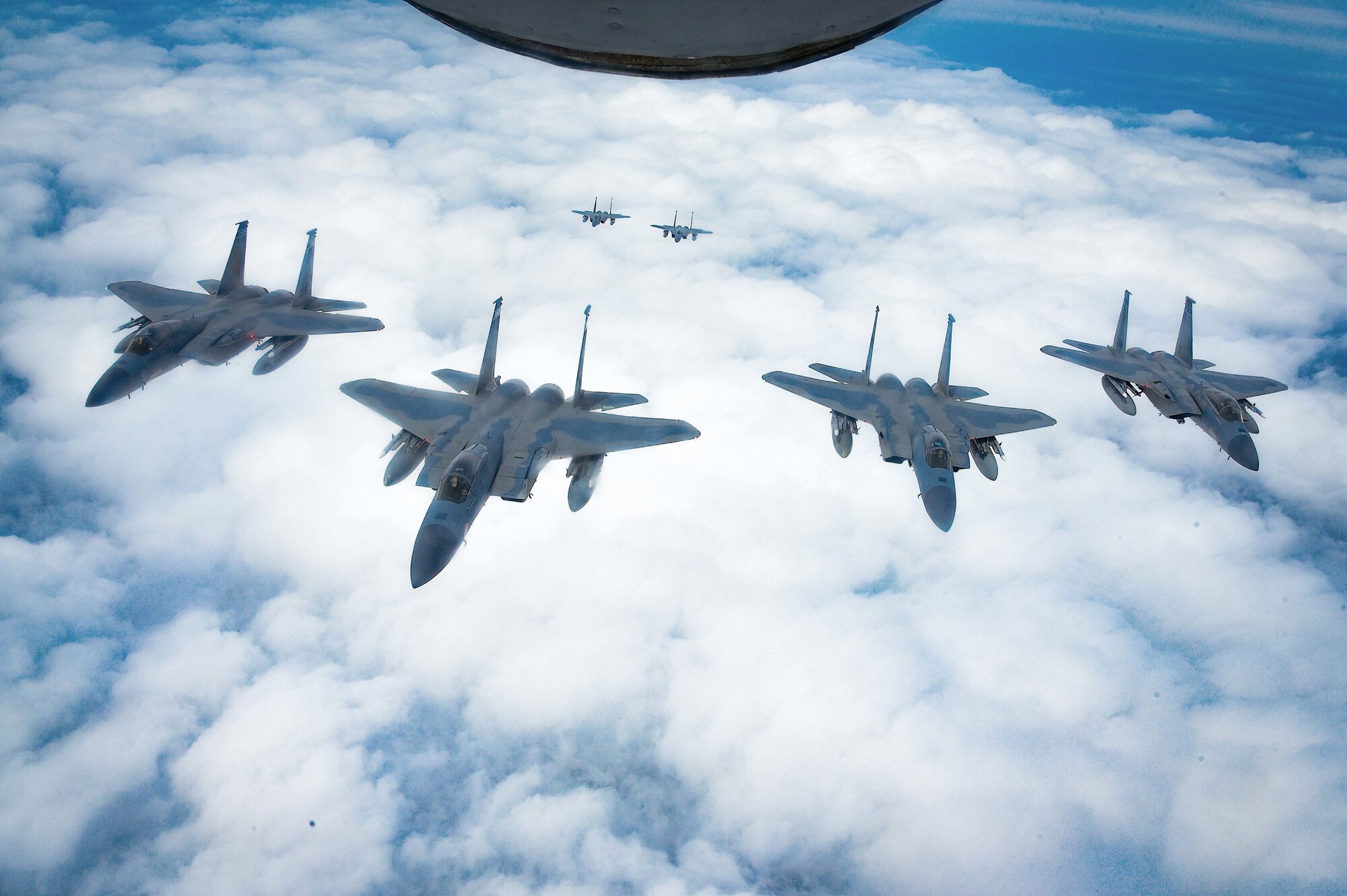 F-15 aircraft flying in formation above a cloud layer