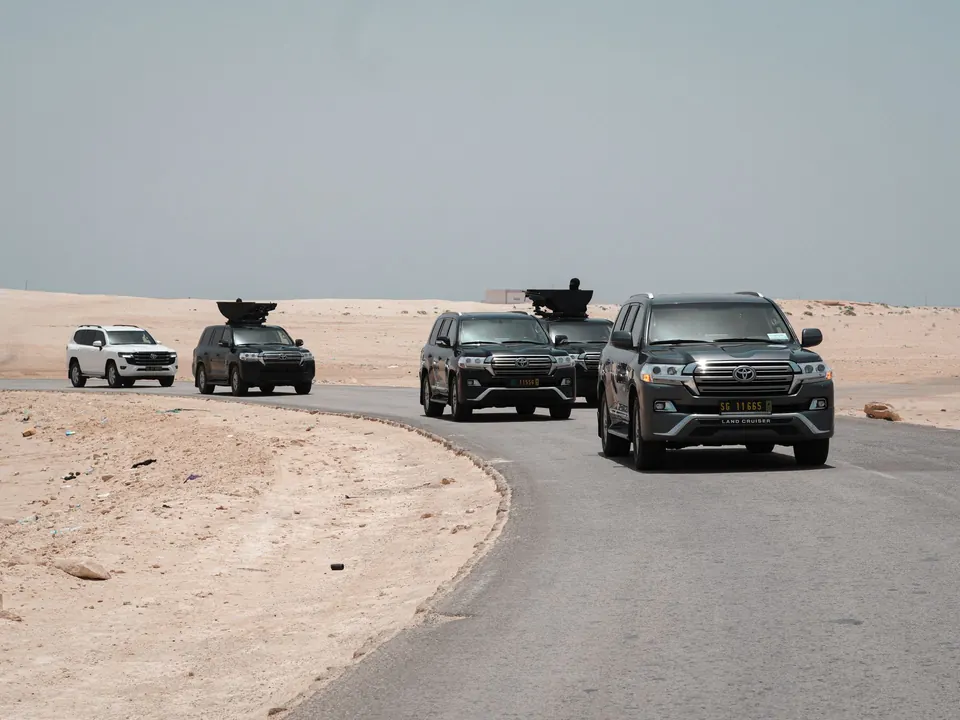 Convoy of armored SUVs on a desert road