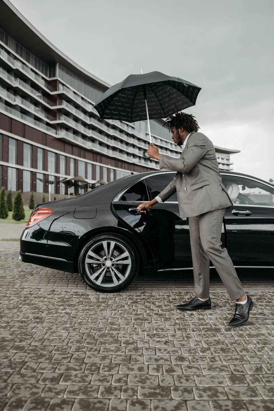 Driver opening a black car door for a client
