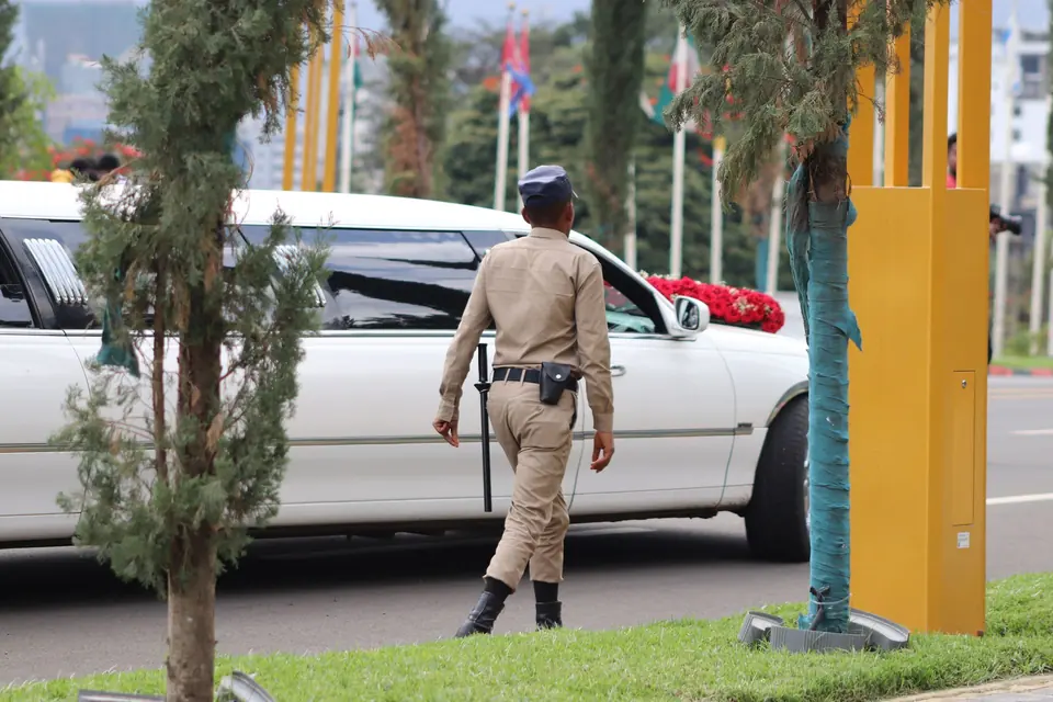 Uniformed officer walking beside a limousine at an event entrance