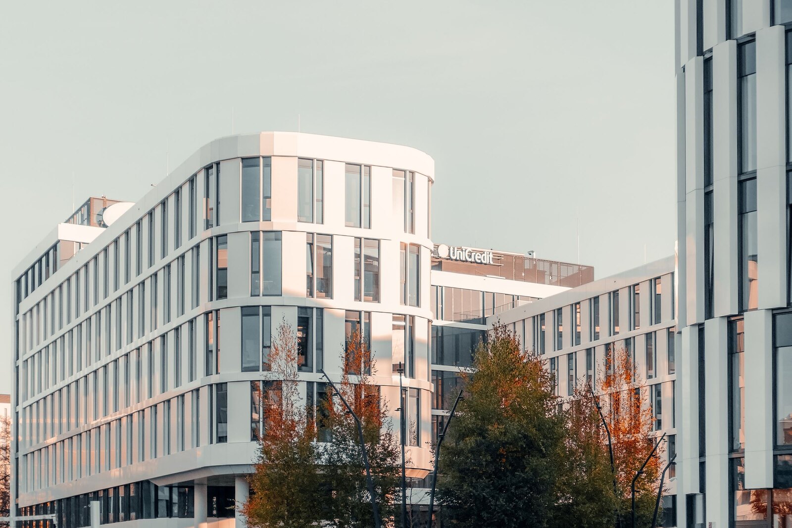 Modern commercial buildings beside a landscaped lawn and trees.