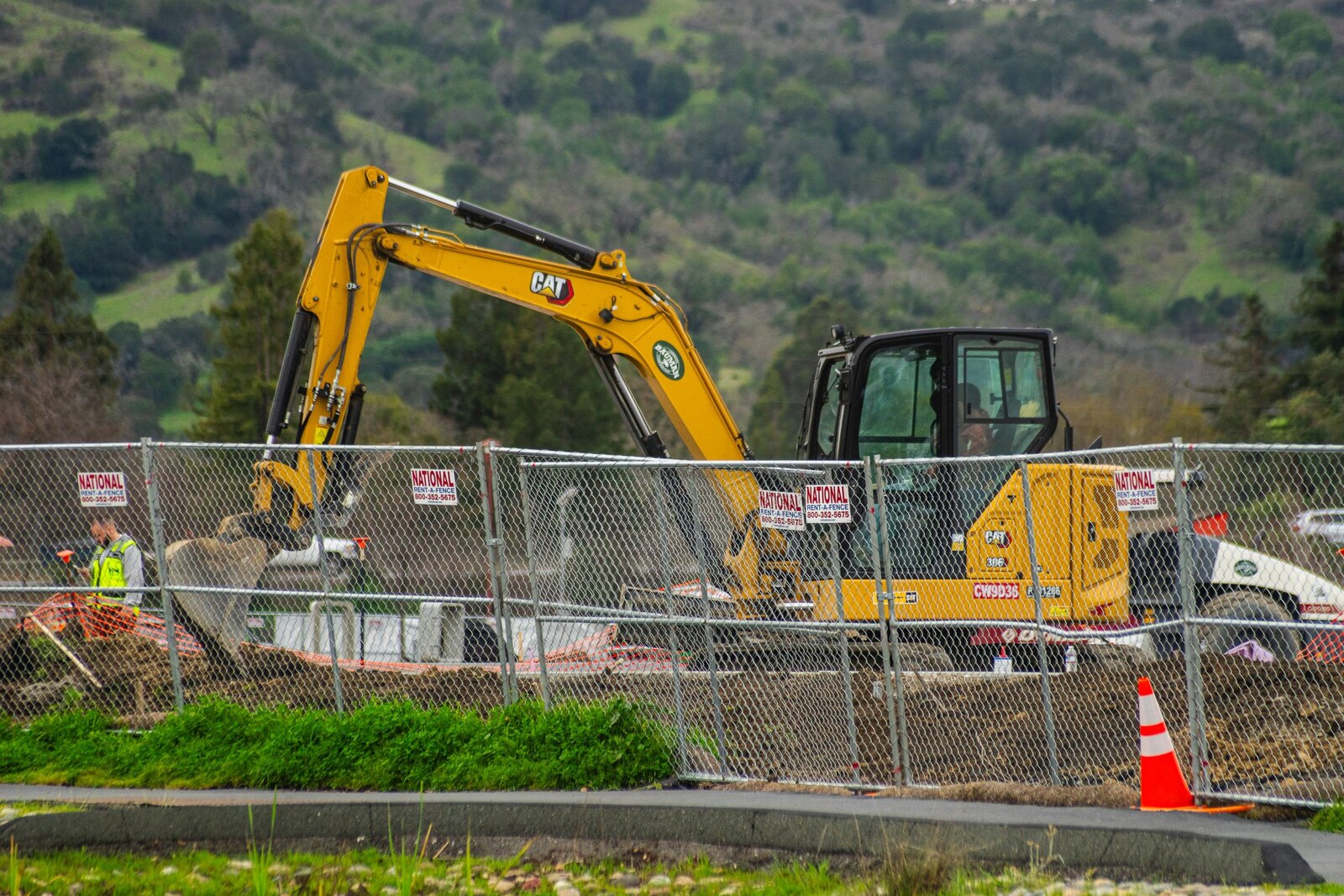 Excavator working behind a construction fence.