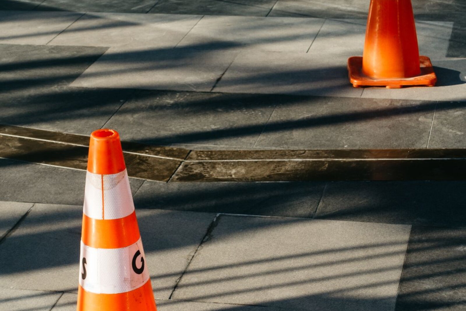 Traffic cones on a paved sidewalk.