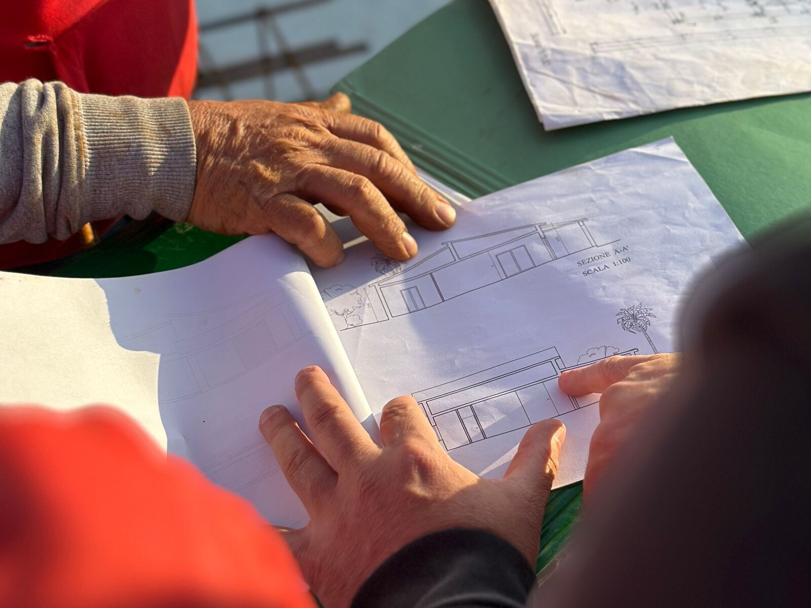 Hands reviewing construction blueprints outdoors.