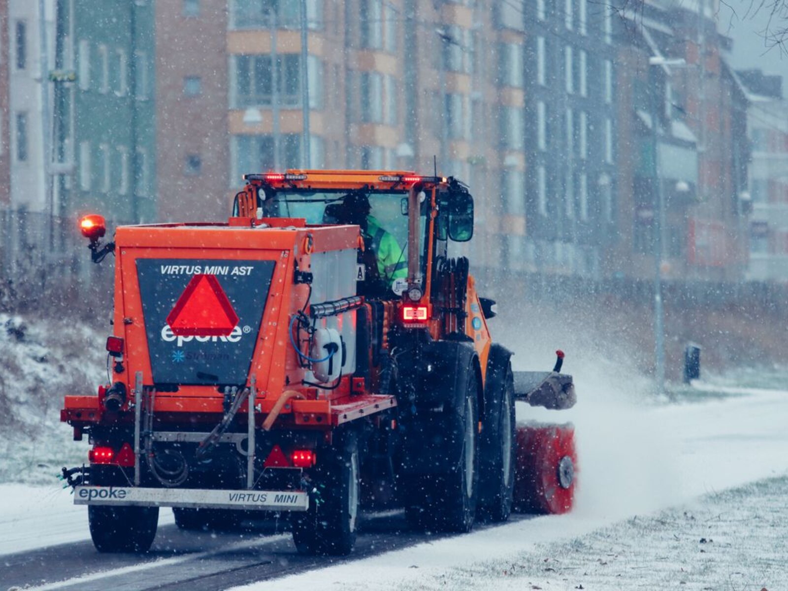 Snowplow clearing a city street in winter.